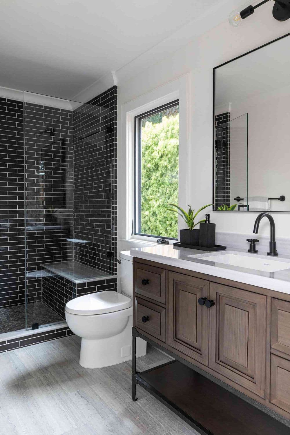 Modern bathroom design with black tile shower, wood vanity, and minimalist decor.