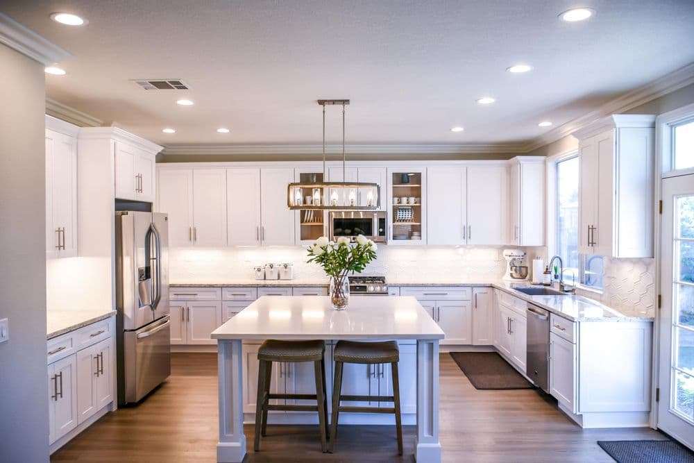 Modern kitchen with white cabinets, stainless steel appliances, and a central island with bar stools.